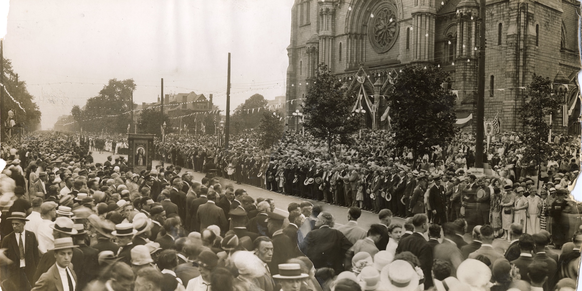 An image of people standing up in wooden pews at church.