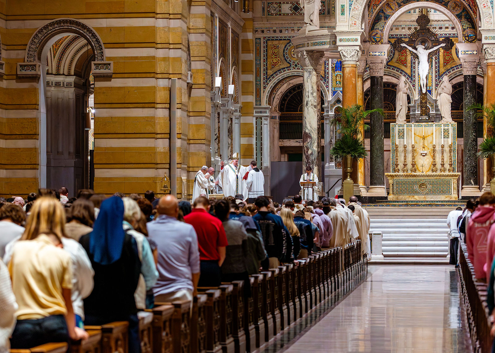 A mass with priests at the altar and people in the pews. The Cathedral Basilica in Saint Louis